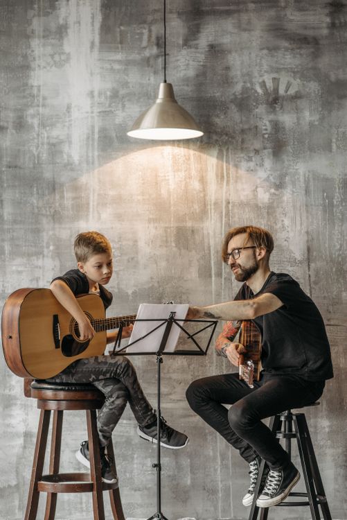 Profesor enseñando guitarra a un alumno — aprender guitarra con ChatGPT e IA