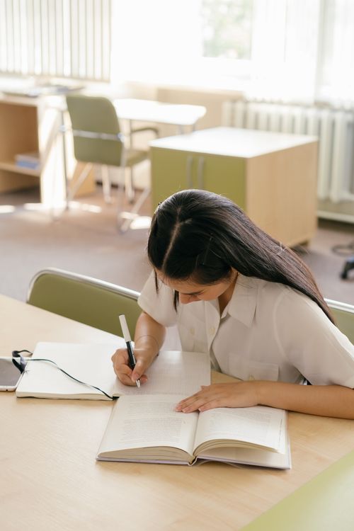 Estudiante en biblioteca escribiendo — detección de plagio con inteligencia artificial